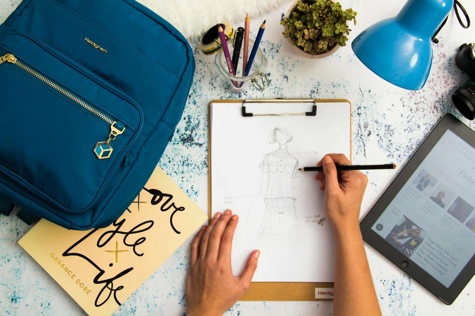 person sketching dress on printer paper with clip board