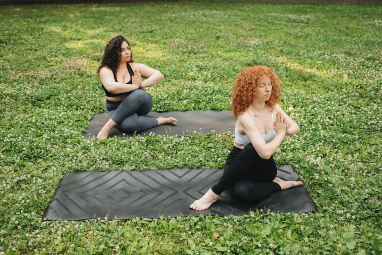 two women doing yoga on the grass
