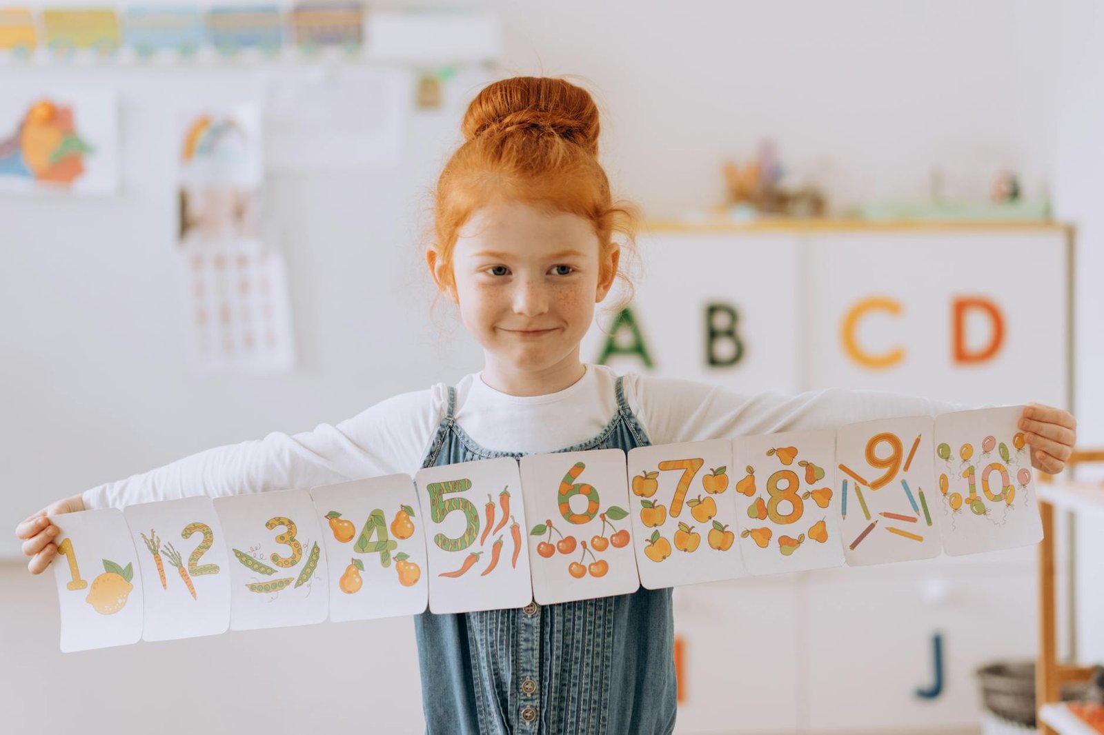 a girl in the classroom holding a paper banner with numbers