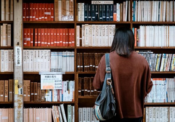 woman wearing brown shirt carrying black leather bag on front of library books