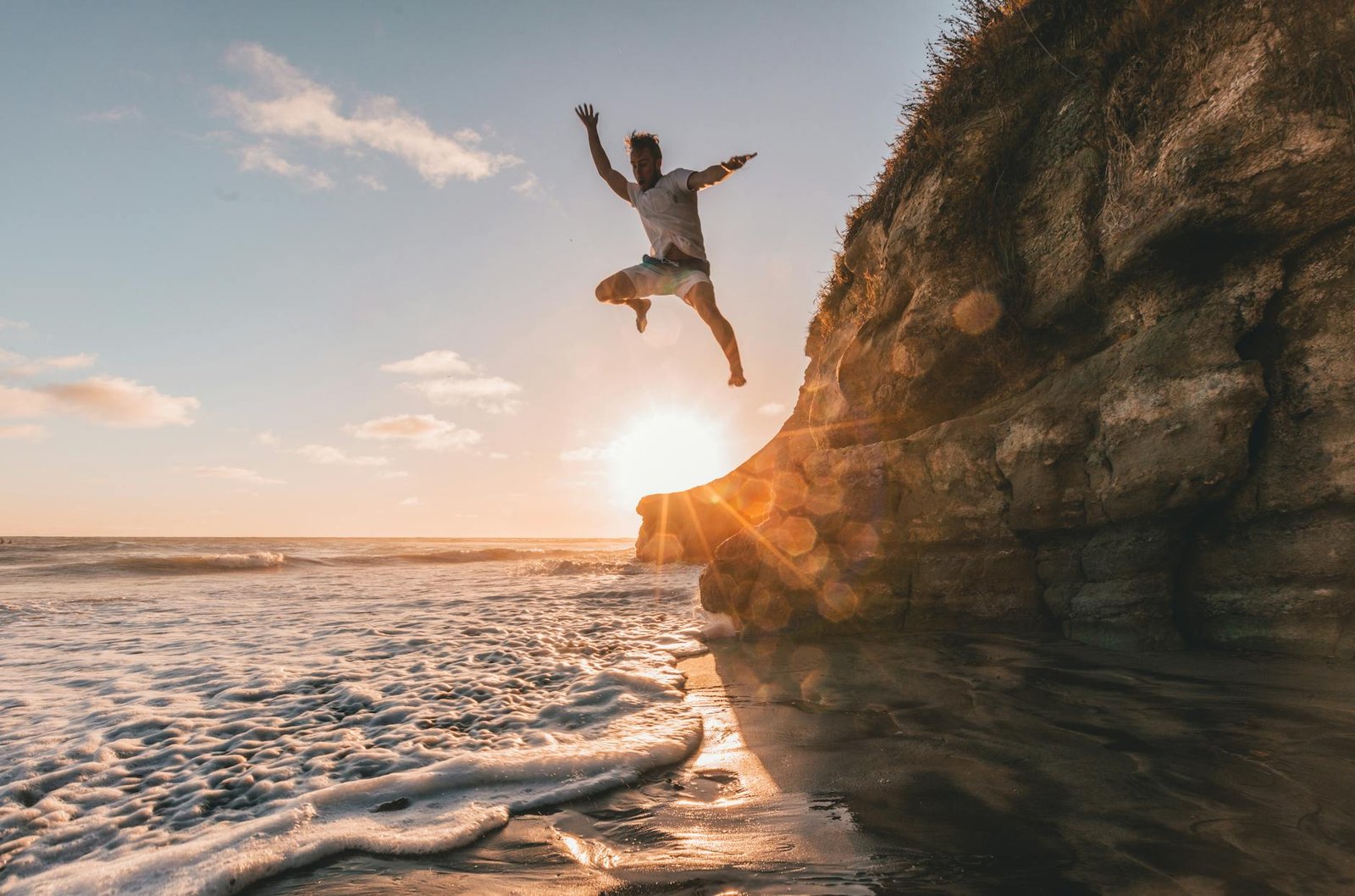 man jumps from cliff to water
