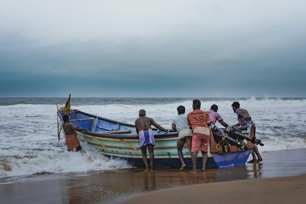 fishermen towing boat on sea shore