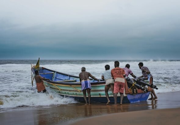 fishermen towing boat on sea shore