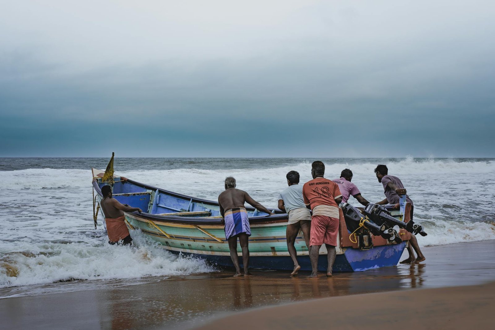 fishermen towing boat on sea shore