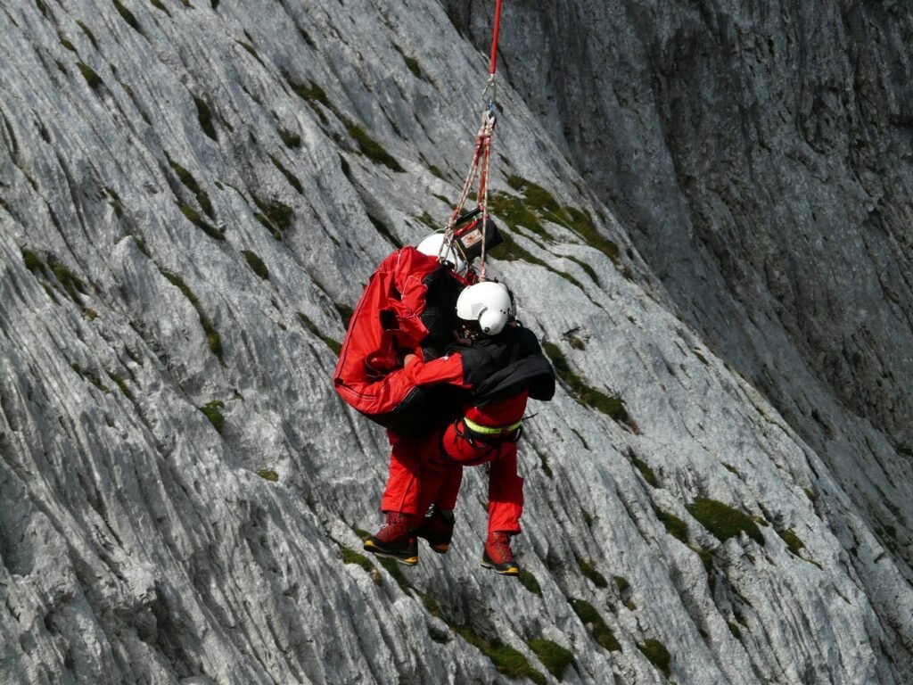 two people rappelling near grey rocks