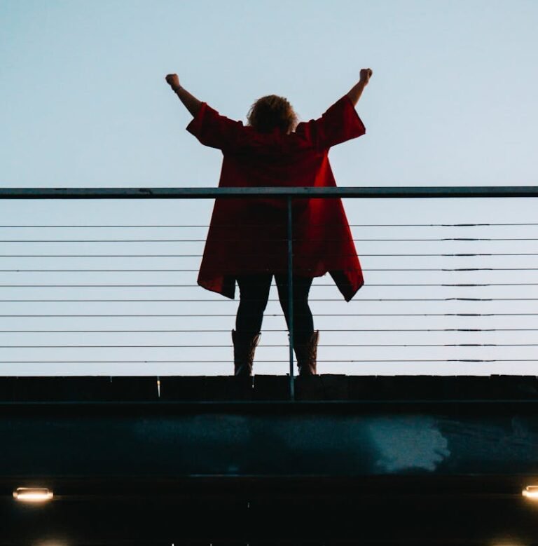 back view photo of standing woman with her hands raised