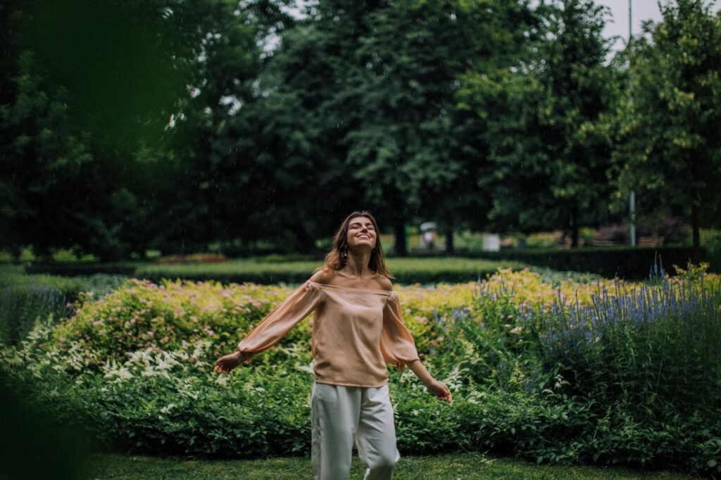 carefree woman standing in the park near a flower garden