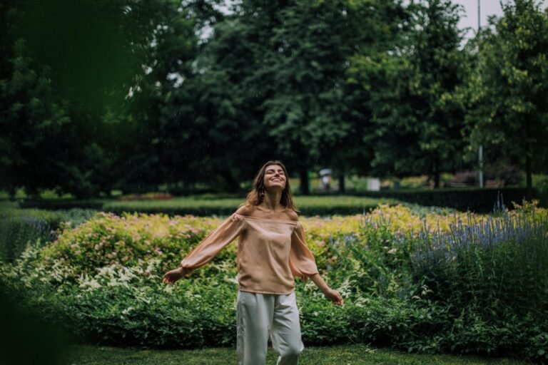 carefree woman standing in the park near a flower garden