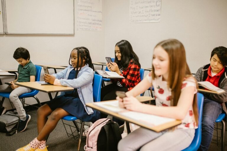 students sitting inside the classroom while using their smartphone