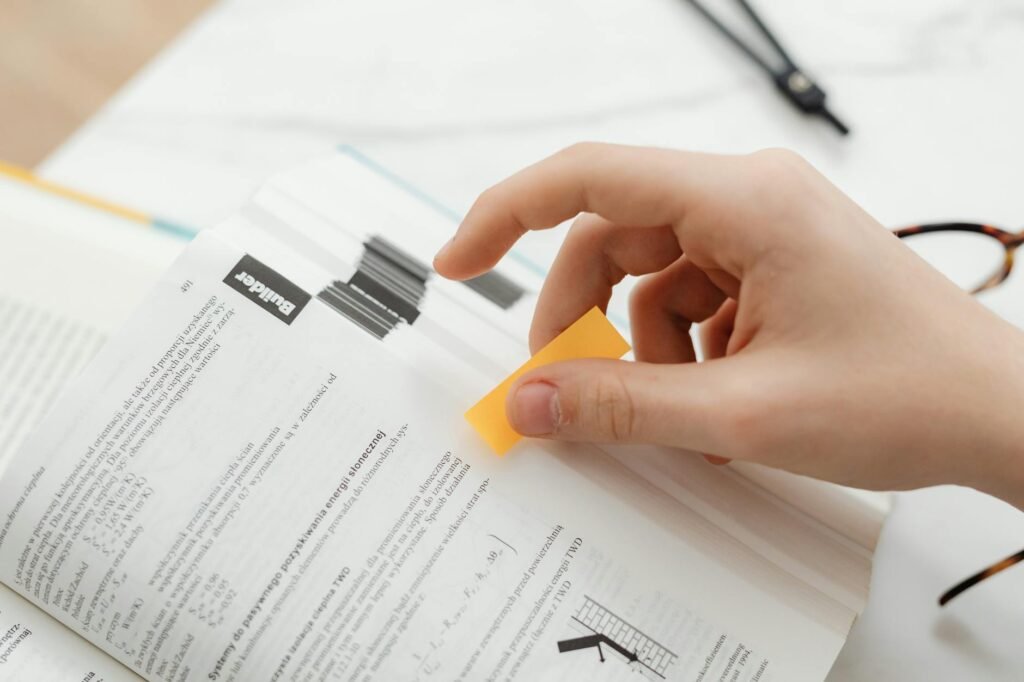 close up of a person putting a sticky note on a textbook page