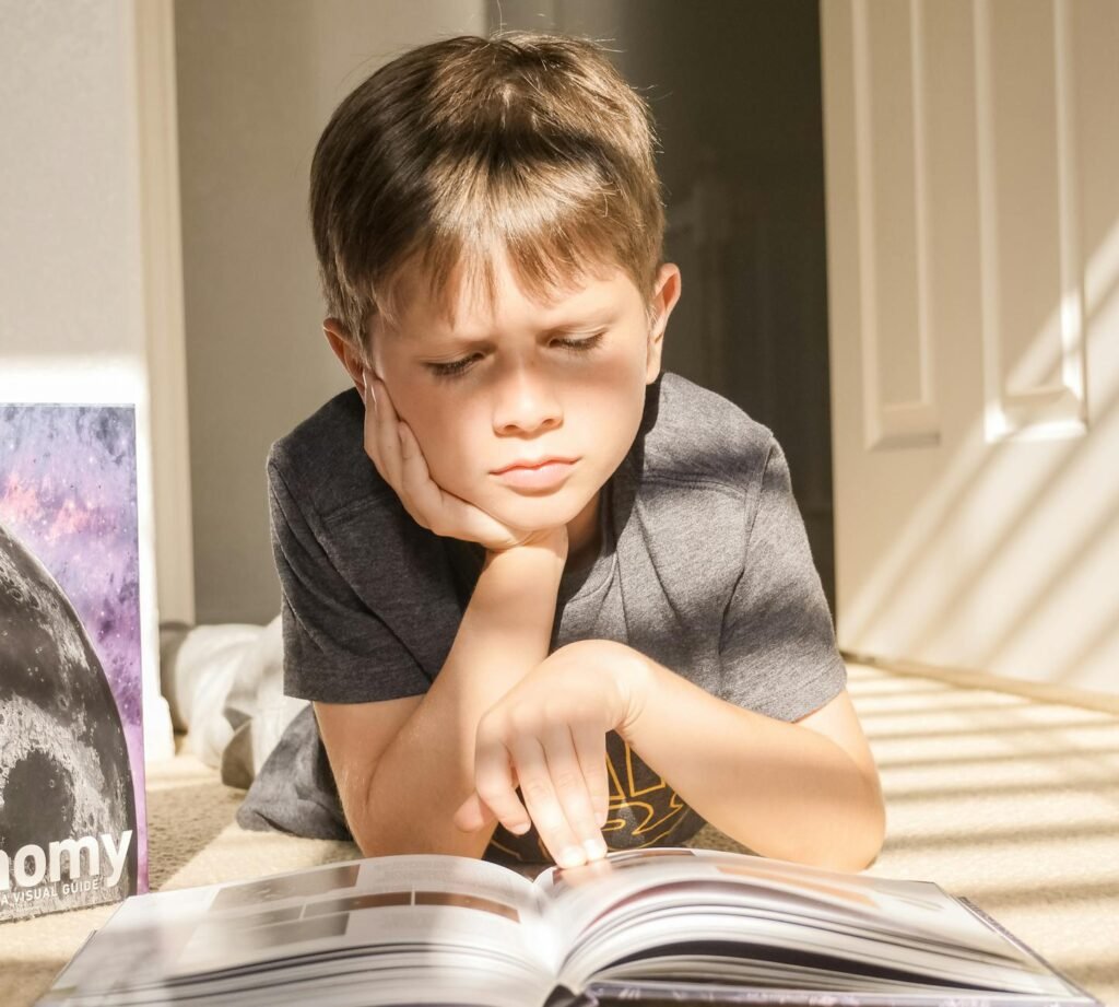 a boy reading a book on the floor