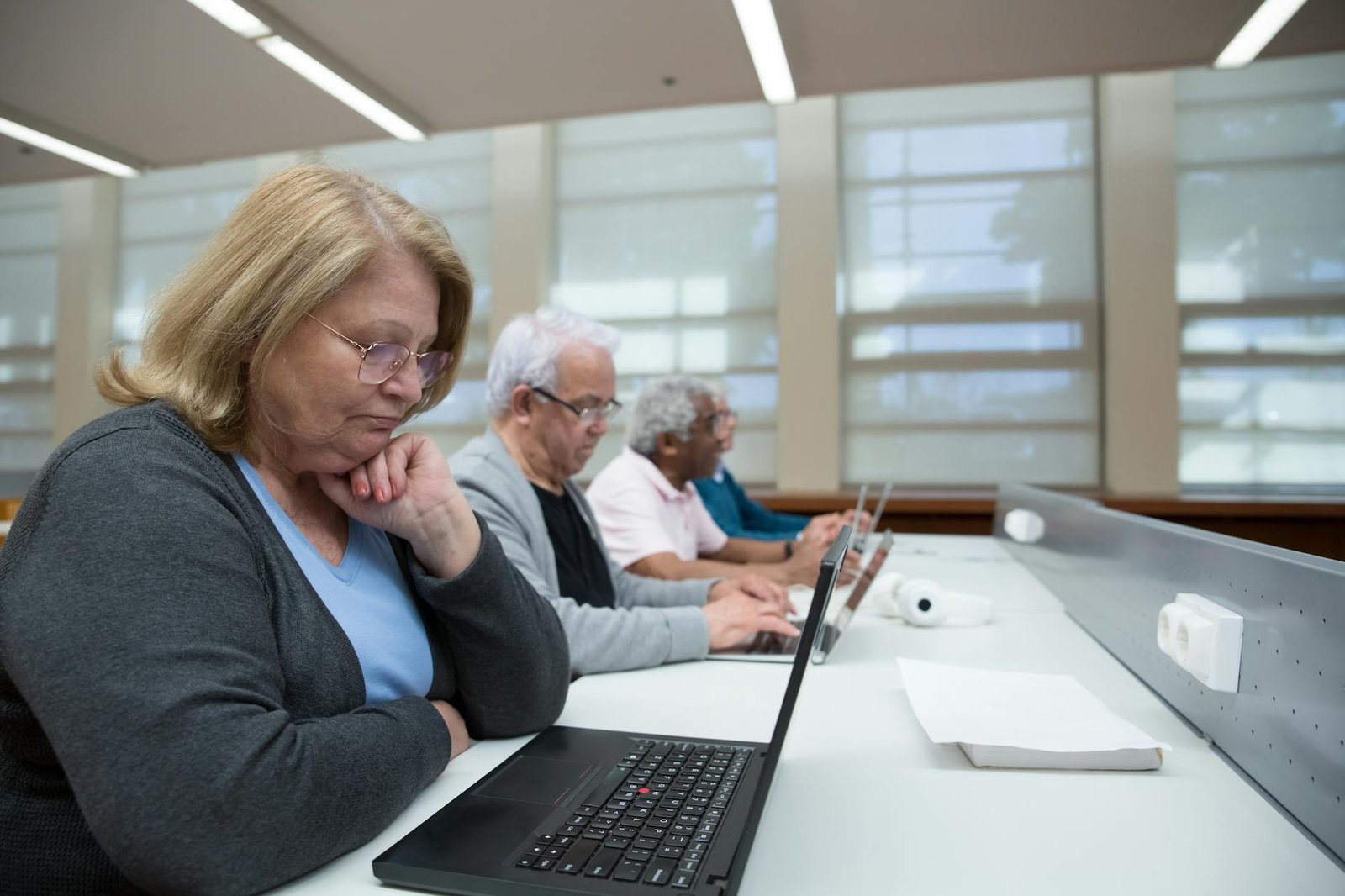 elderly people sitting in a classroom learning to use computers
