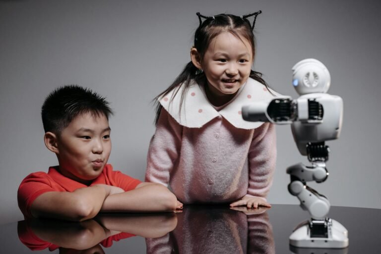 a young girl and boy looking at the robot on the table