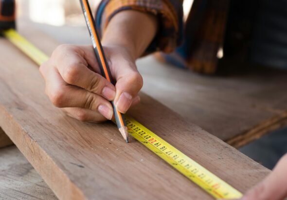 woman measuring with yellow pencil on board