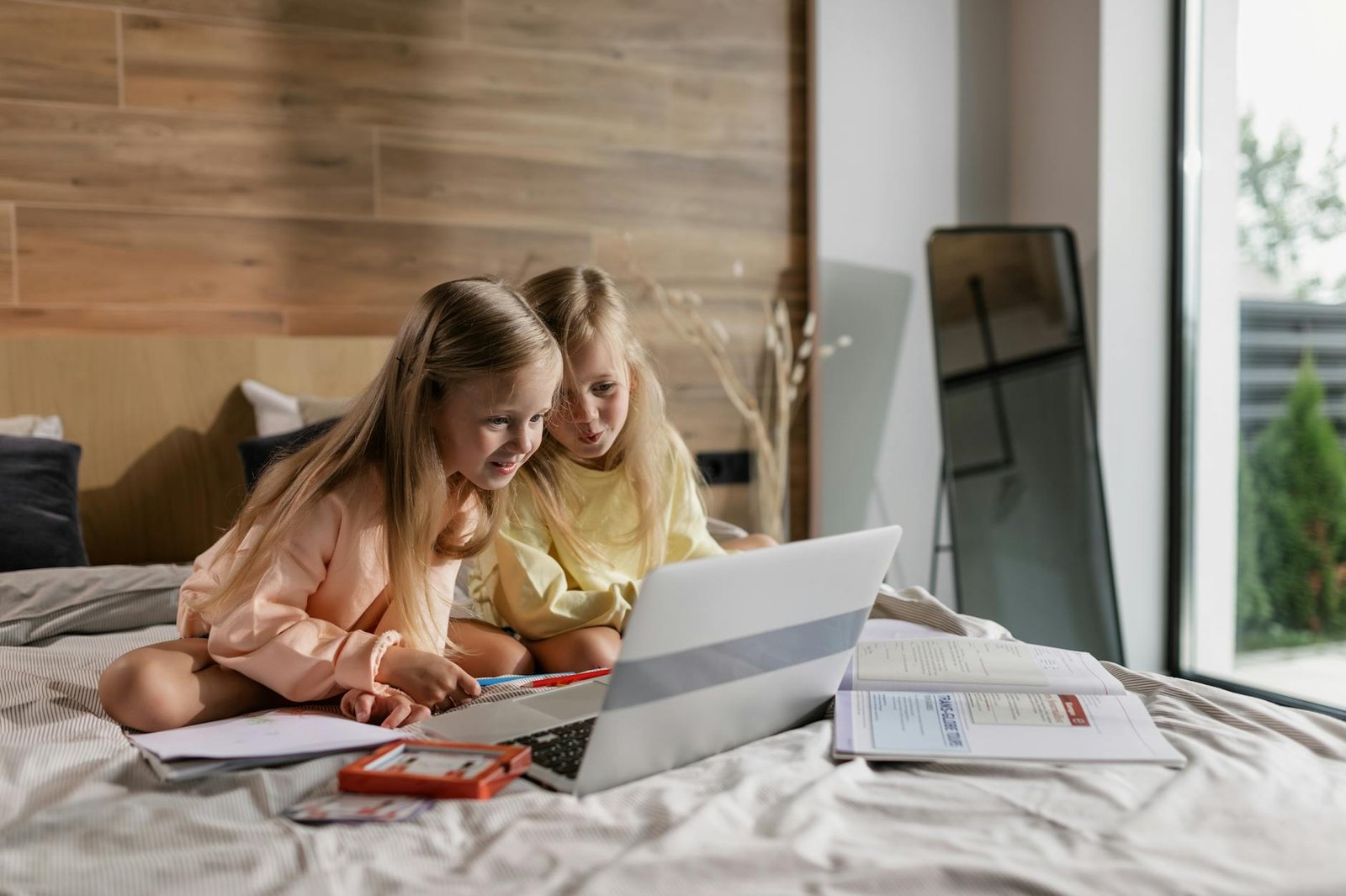 two girls having an online class while sitting on the bed