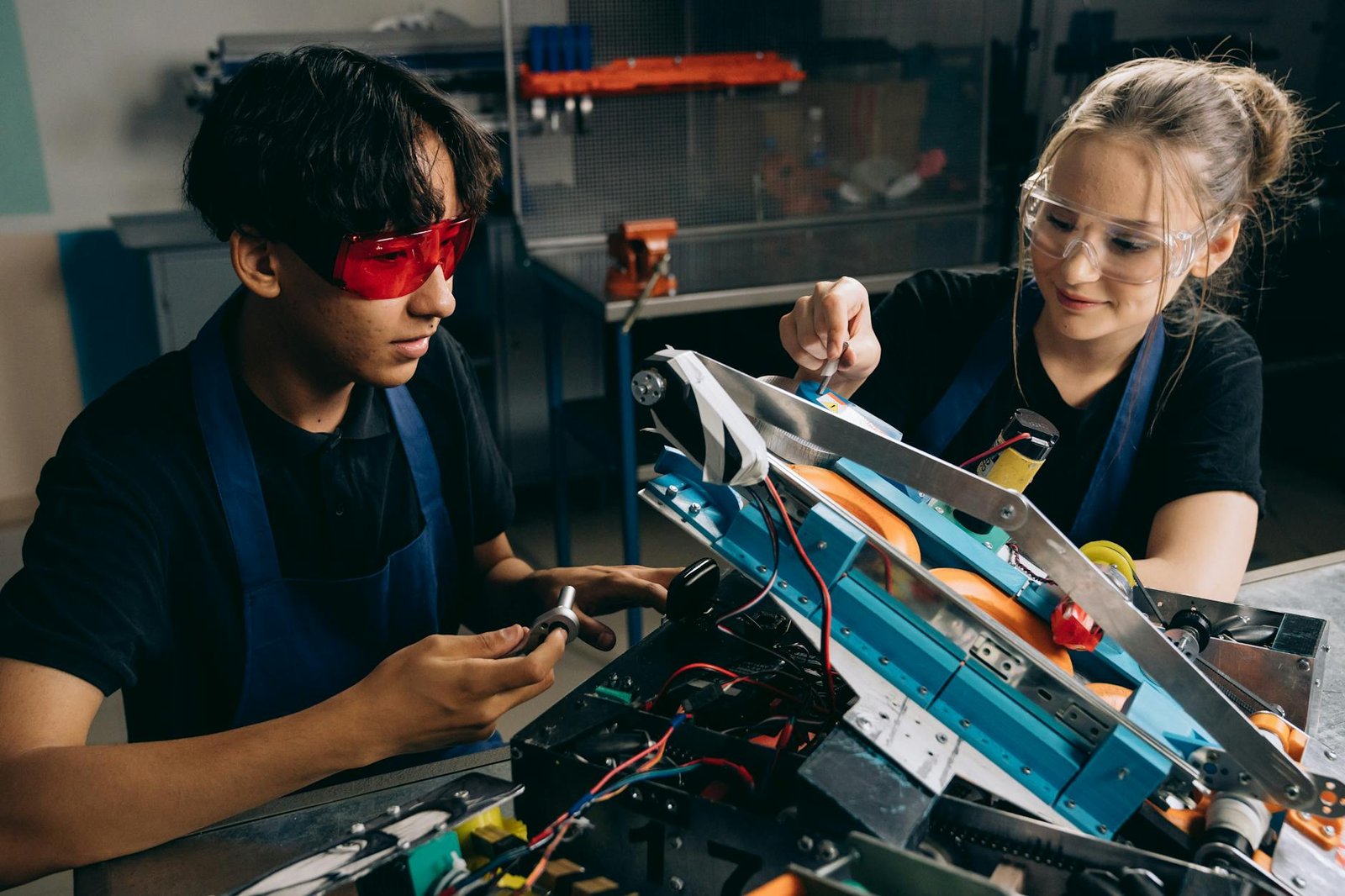 woman and man in goggles sitting by table and working on electronics