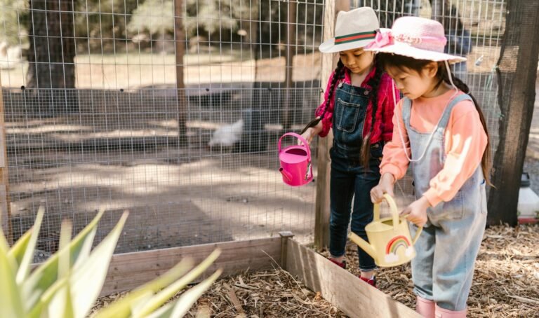two young girls using watering cans for gardening